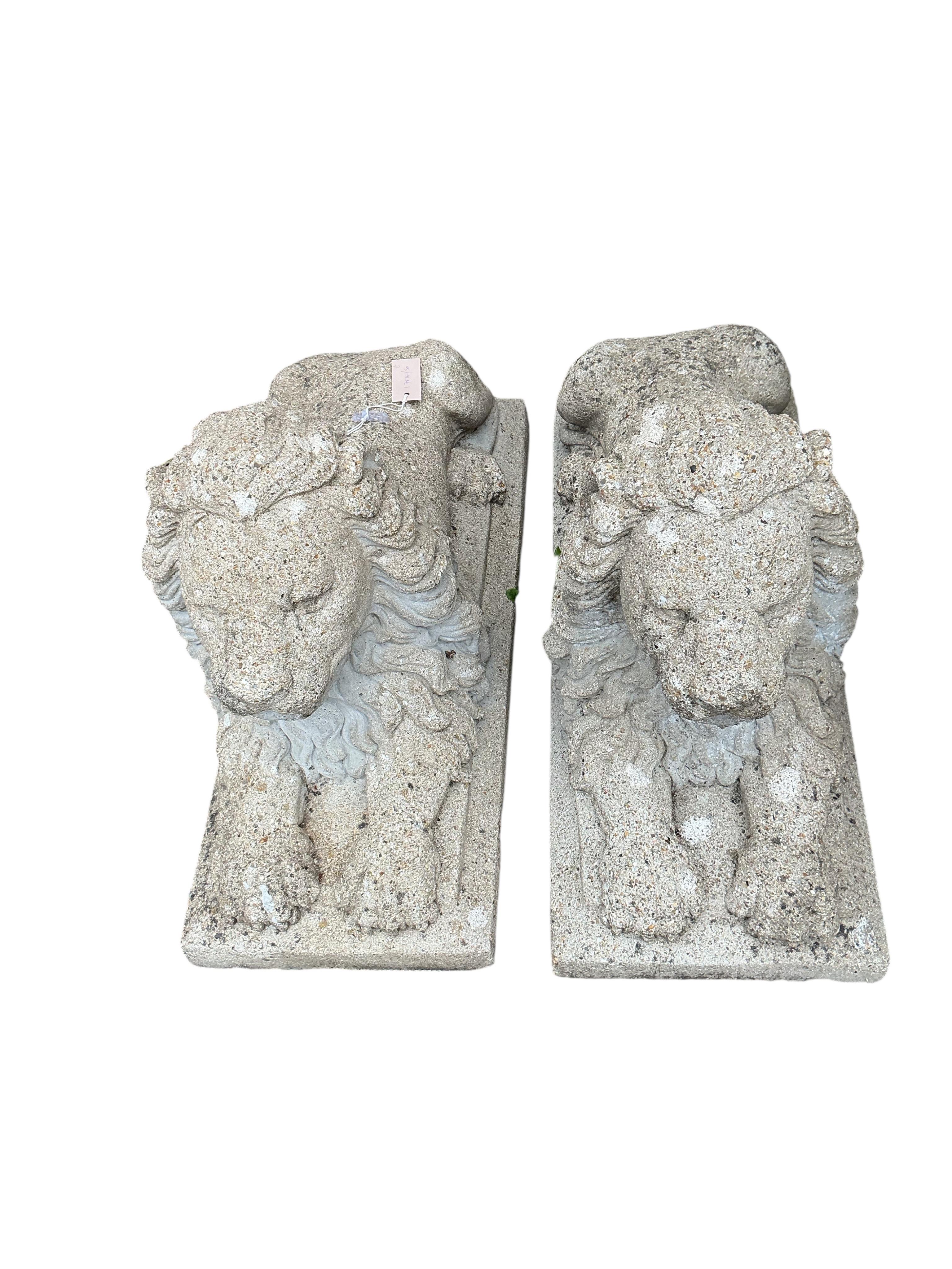 A pair of reconstituted stone lion garden ornaments, length 81cm, height 50cm